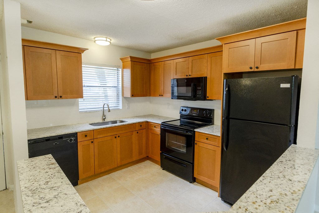 A kitchen with black appliances and wooden cabinets.